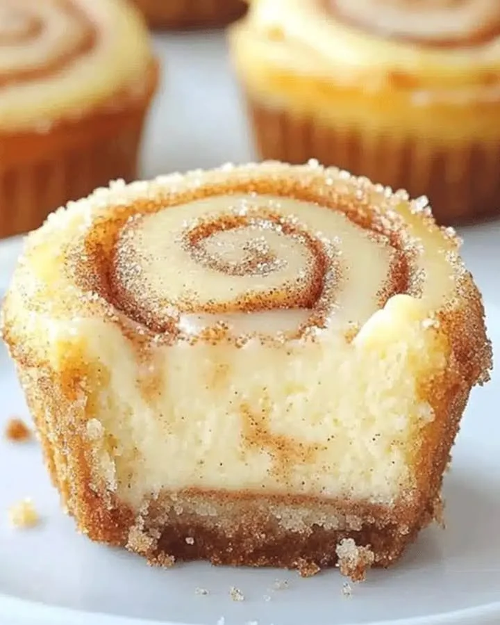 Mini cinnamon roll cheesecakes topped with cream cheese frosting and cinnamon swirls.